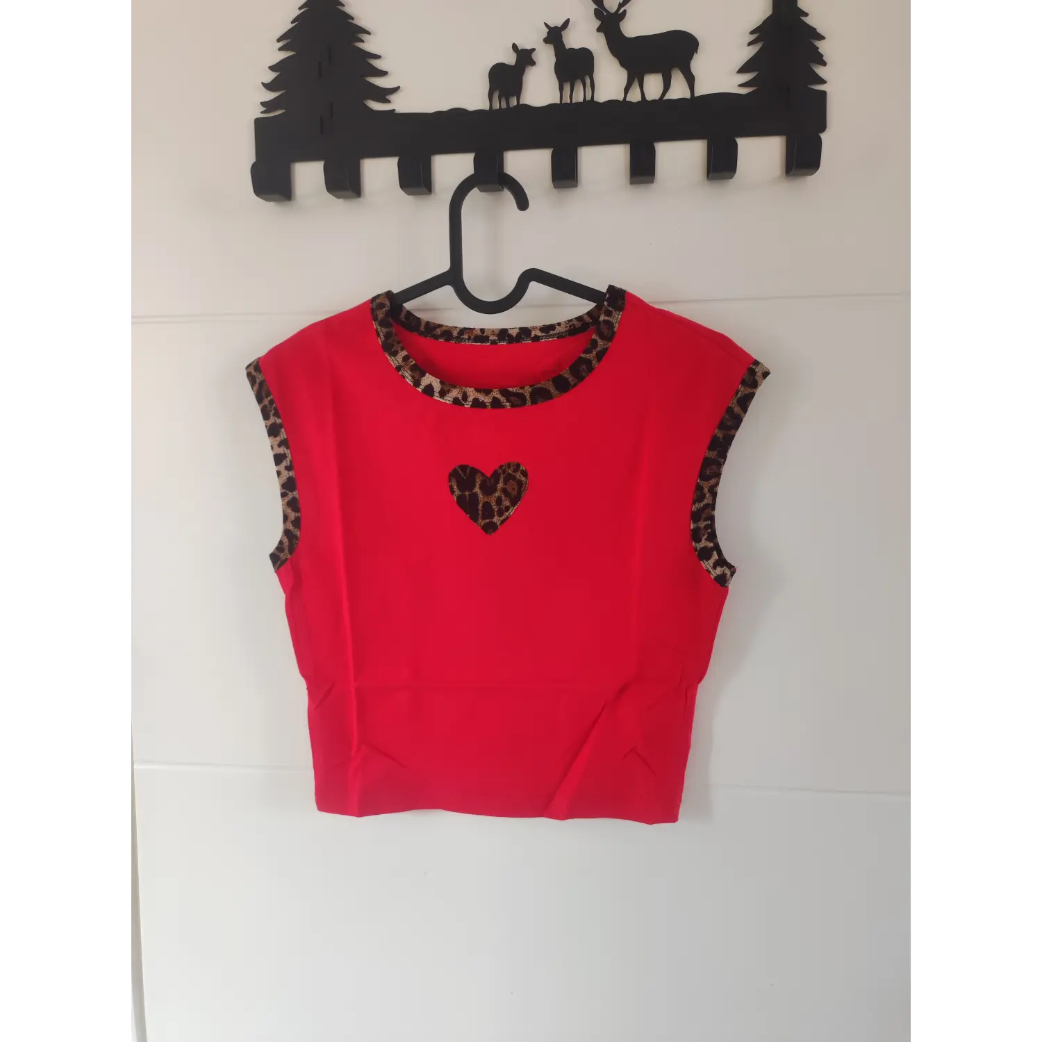 Front view on hanger, red sleeveless crop top with leopard trim and leopard heart patch