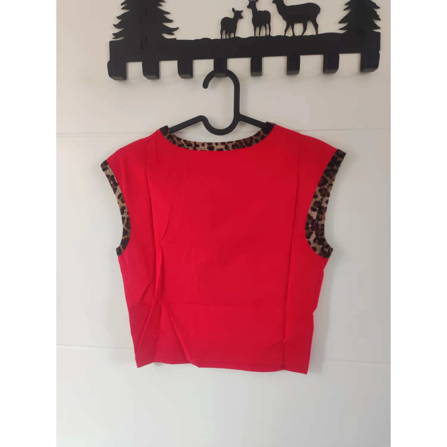 Back view on hanger, bright red sleeveless cropped top with leopard print neckline and armhole trim