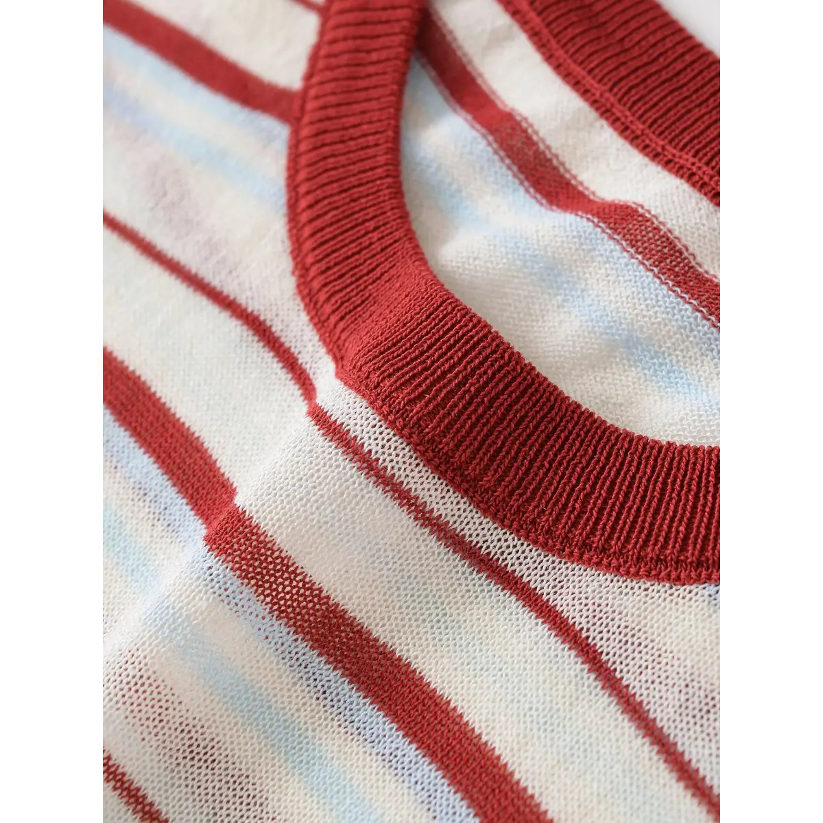 Close-up of the crew neck on the red and light blue striped knit top, showing the ribbed trim and semi-sheer mesh texture