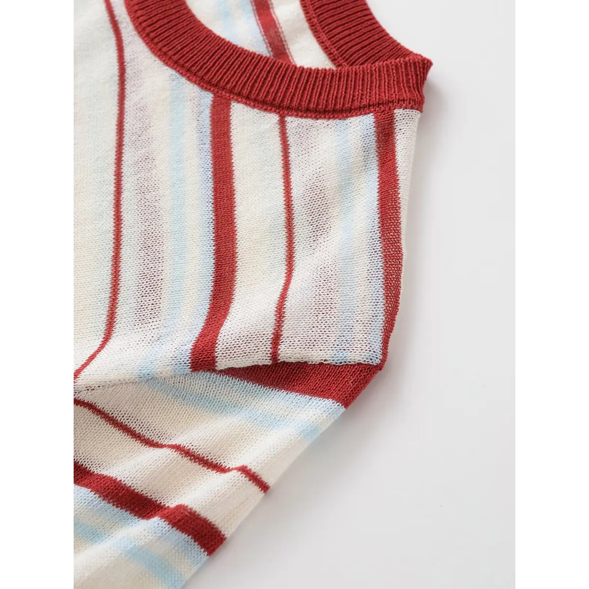 Shoulder detail of the red and light blue striped knit top, showing the ribbed crew neck and semi-sheer fabric