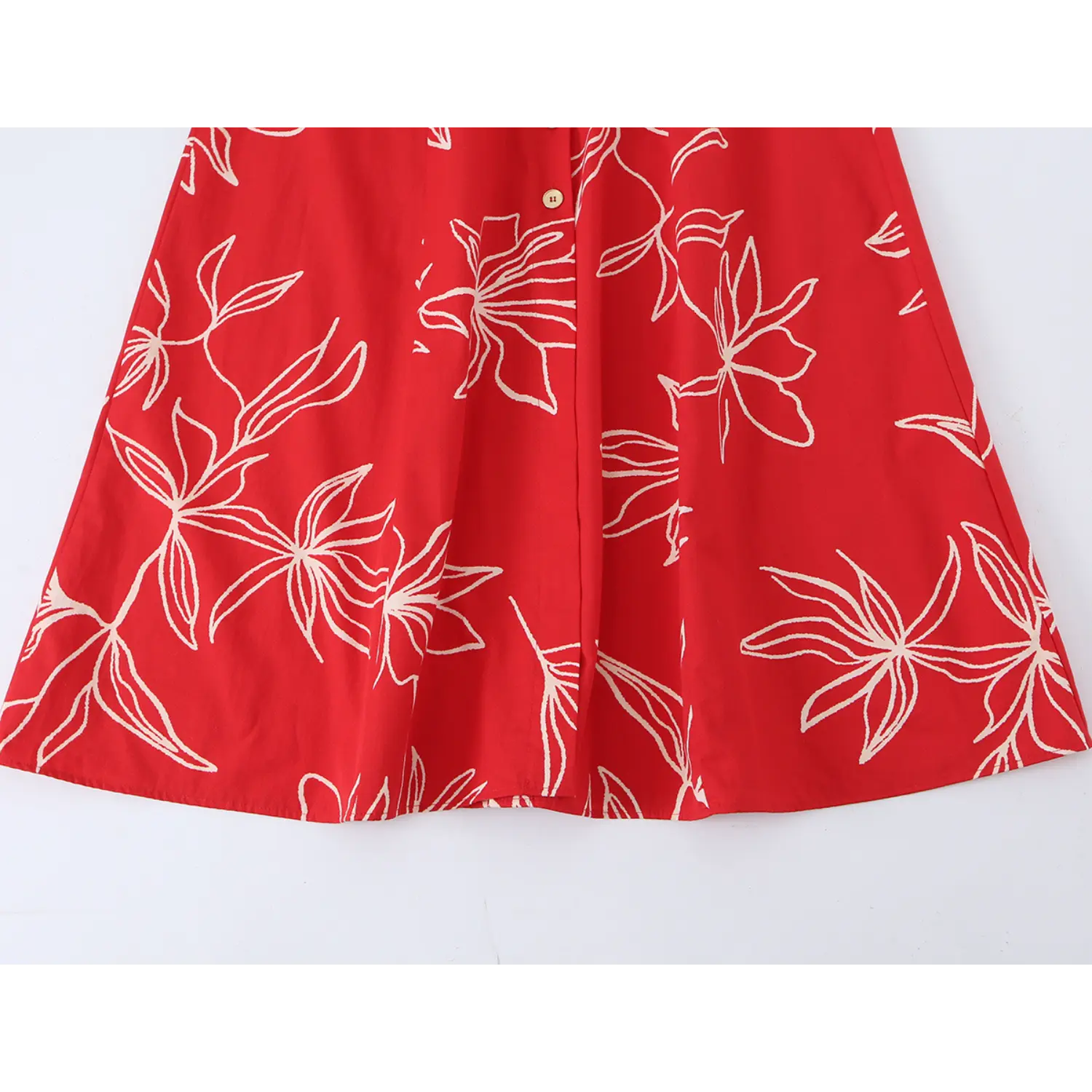 Close-up shot of the skirt hem of red halter midi dress with off-white line floral print and front button detail