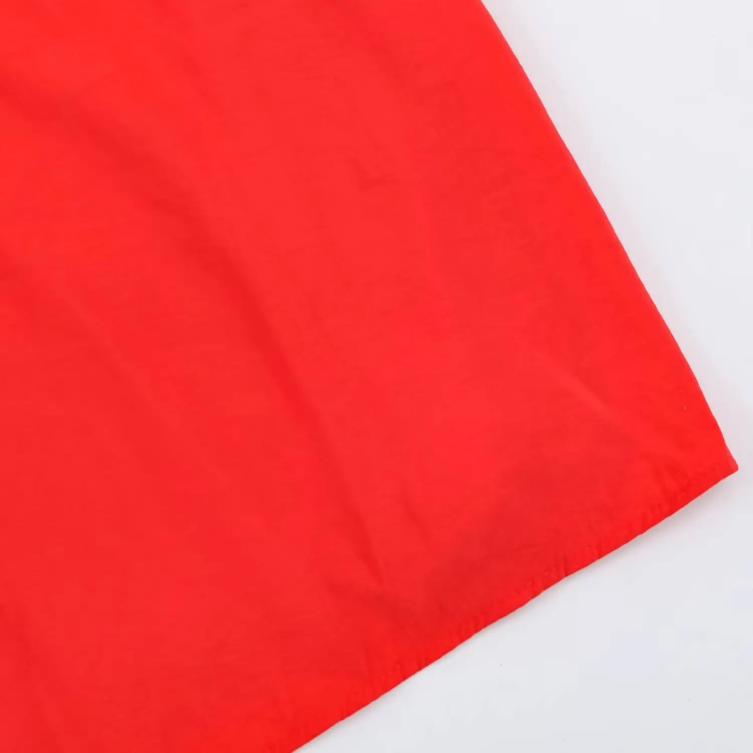 Close-up of skirt bottom hem, neat finished edge on red lightweight woven fabric