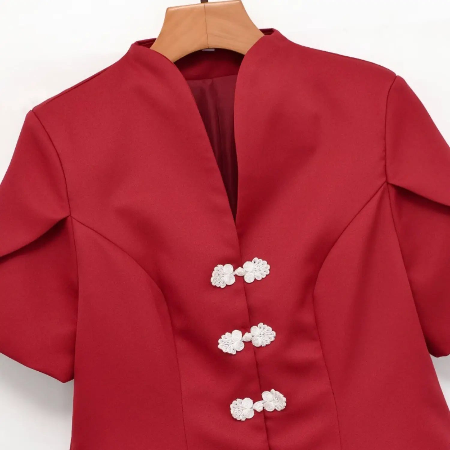 Close-up of red new chinese top front, decorative white floral frog buttons, v neck collar detail