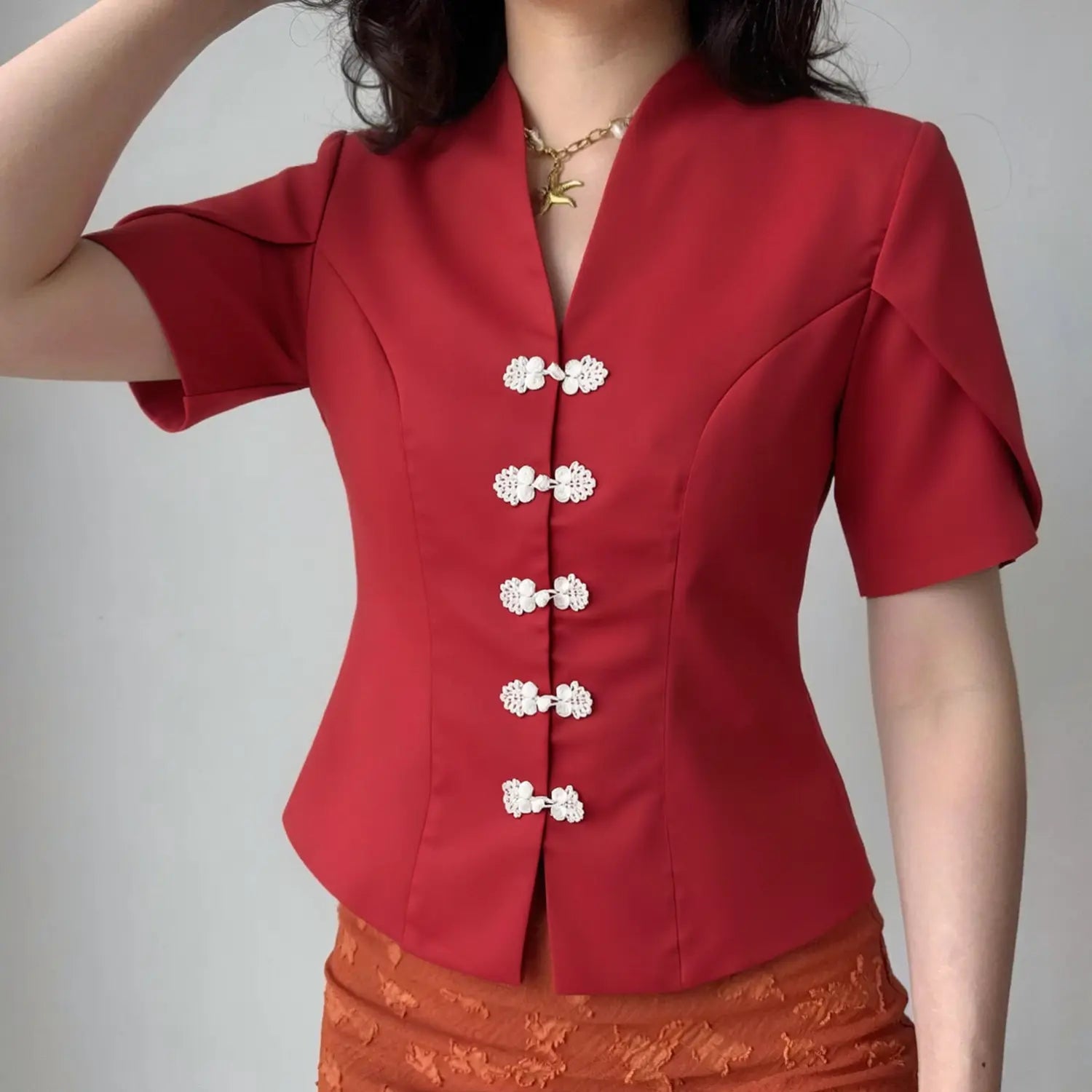 Model wearing red new chinese v neck short sleeve top with white frog buttons, fitted peplum hem