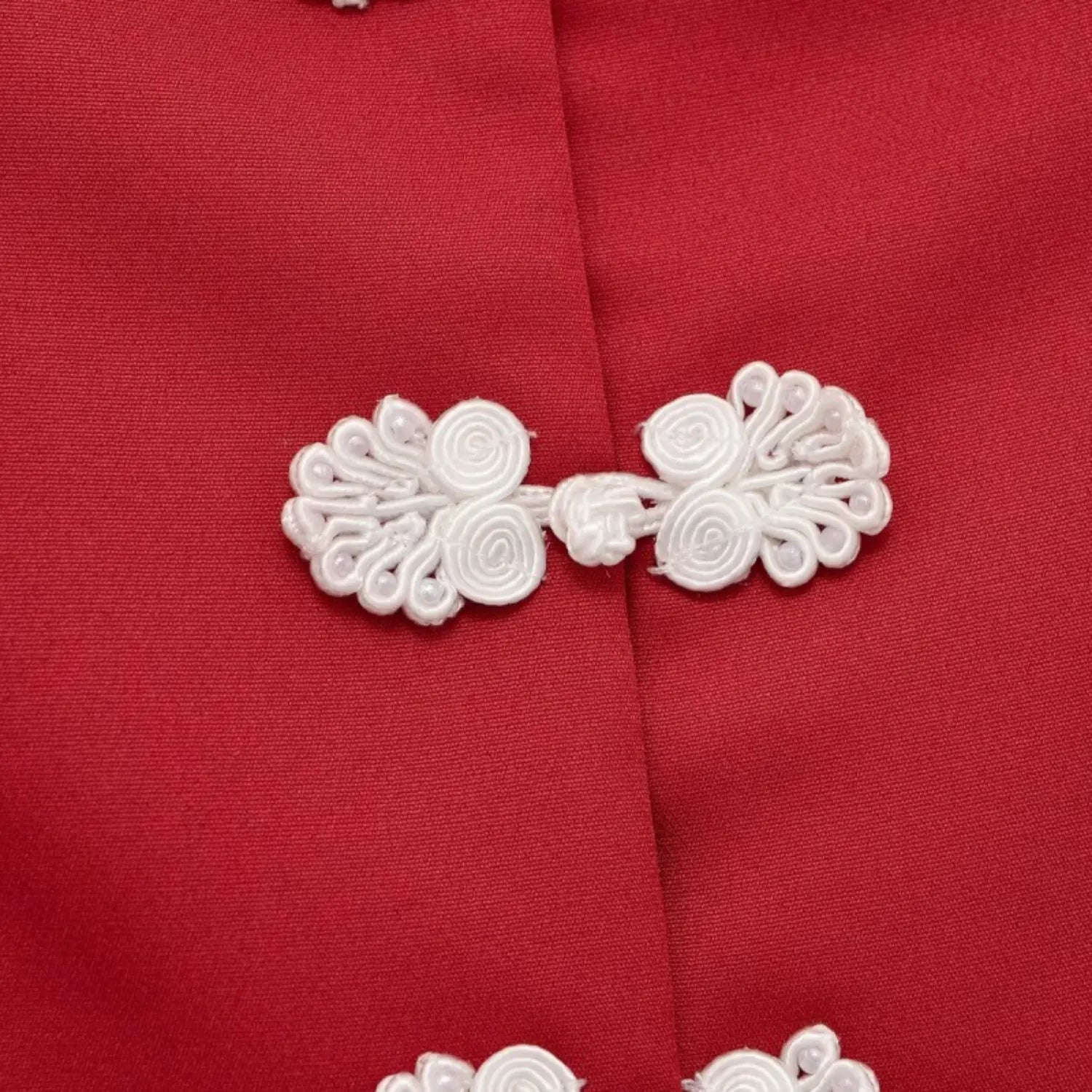 Close up of white decorative frog button on red new chinese style short sleeve top, handmade knot detail