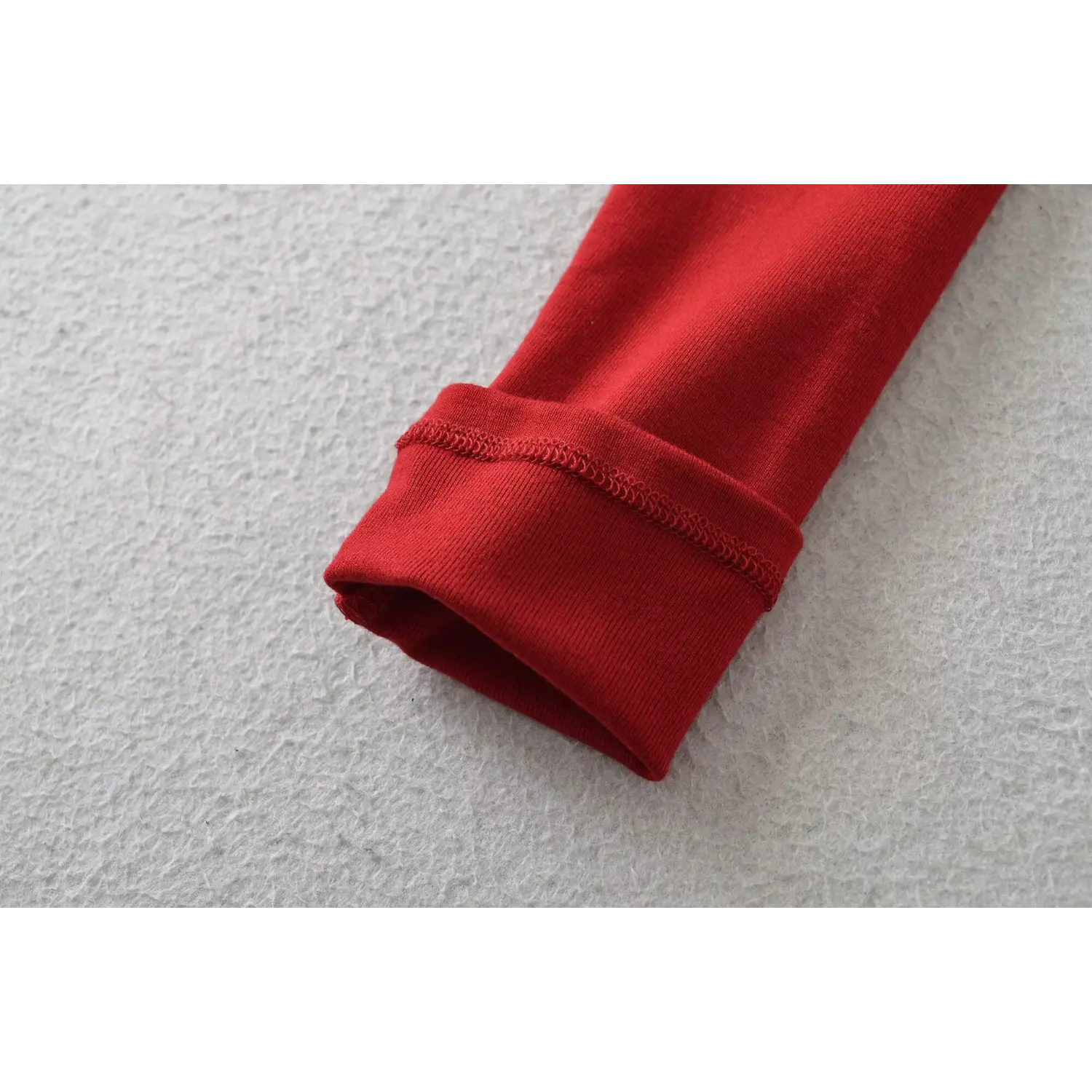 Red cold shoulder long sleeve top cuff flat close-up, double rib overlock stretch knit sleeve hem neat stitching white background shot