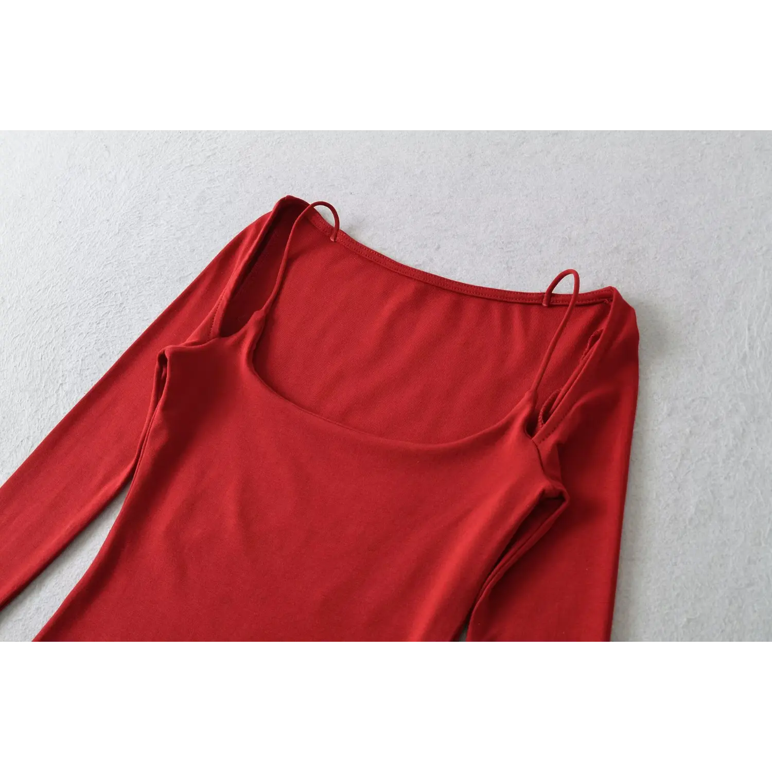 Red cold shoulder long sleeve top u neck flat close-up, wide u scoop neck thin strap overlock stitching black lace inner binding detail white background shot
