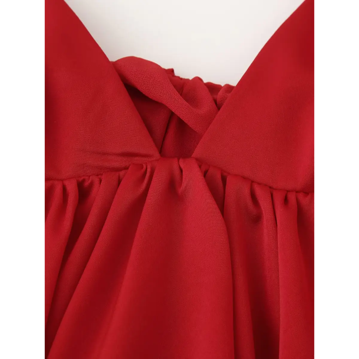 Close-up of the front V-neckline on the red cami top, showing the gathered bust seam and smooth fabric texture