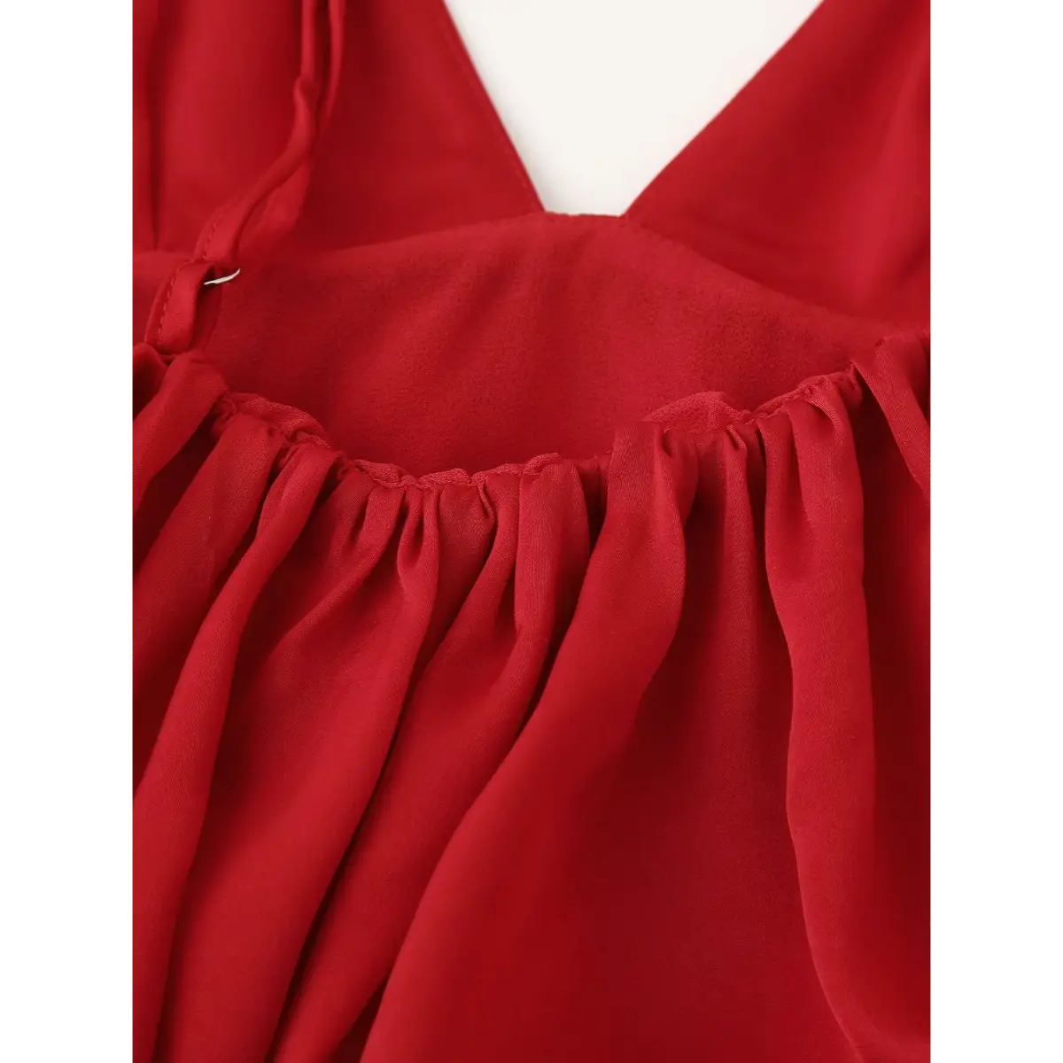 Close-up of the gathered bust detail on the red peplum cami top, showing the smooth fabric and elasticated seam