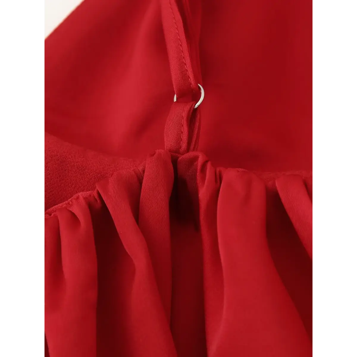Close-up of the strap adjustment slider on the red cami top, showing the metal ring and gathered fabric