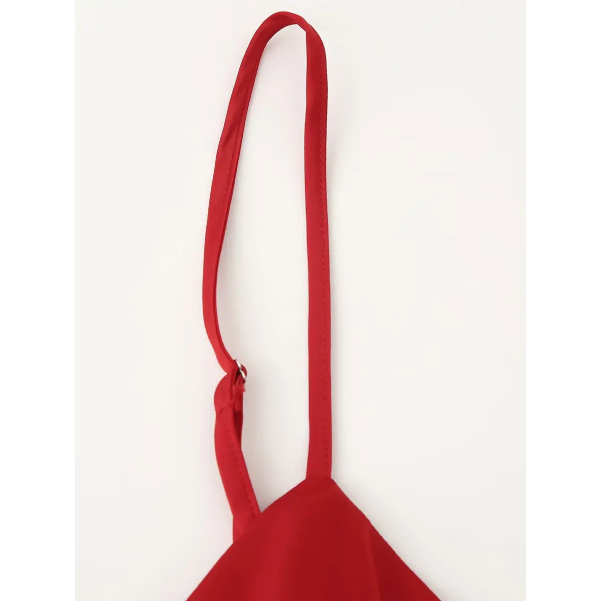 Close-up of the adjustable spaghetti strap on the red cami top, showing the slider mechanism and neat stitching