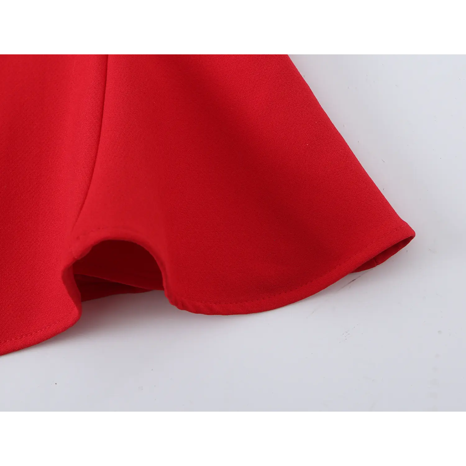 Close‑up of finished flared peplum hem, clean edge stitching on red halter top