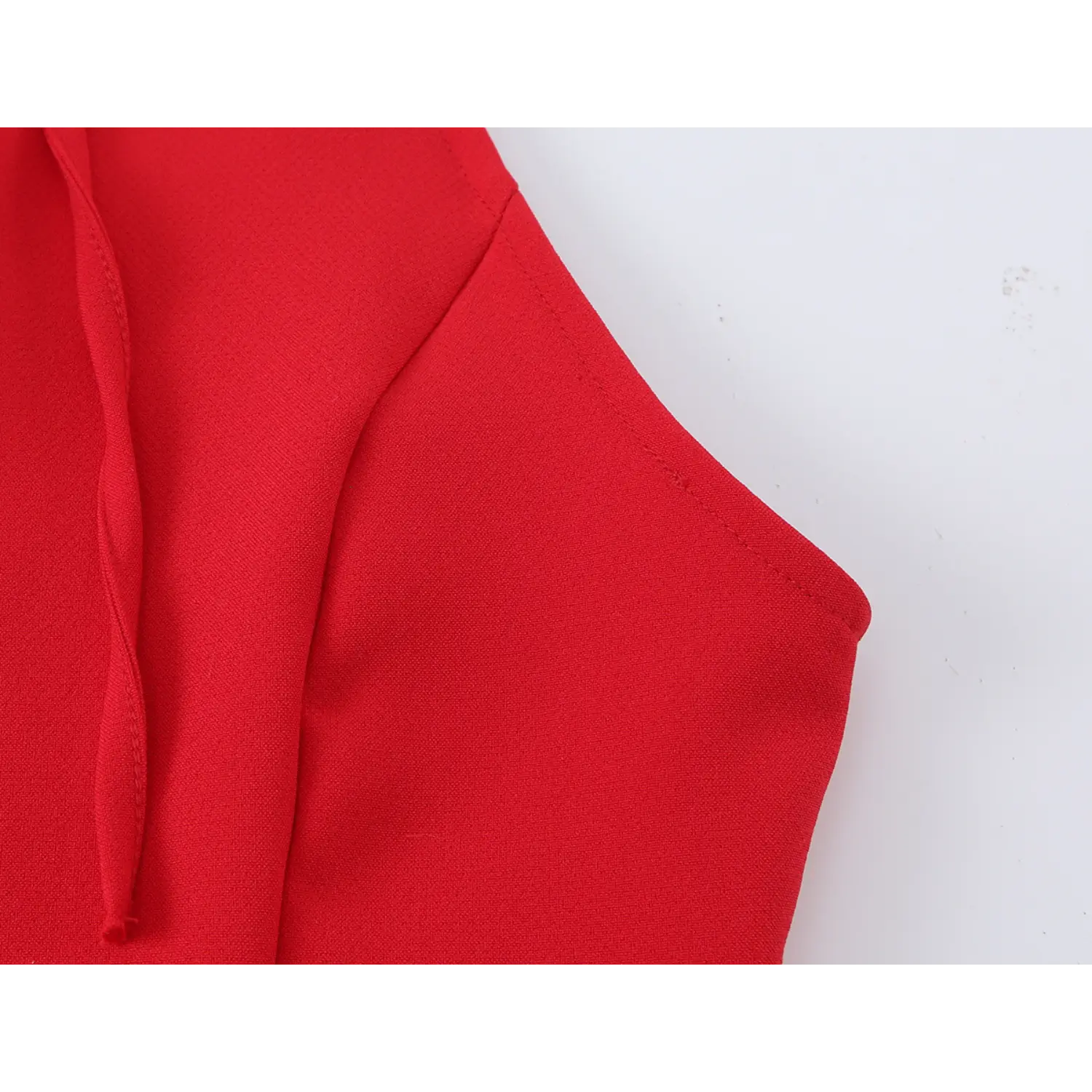 Close‑up of armhole neat stitching, smooth red woven fabric texture