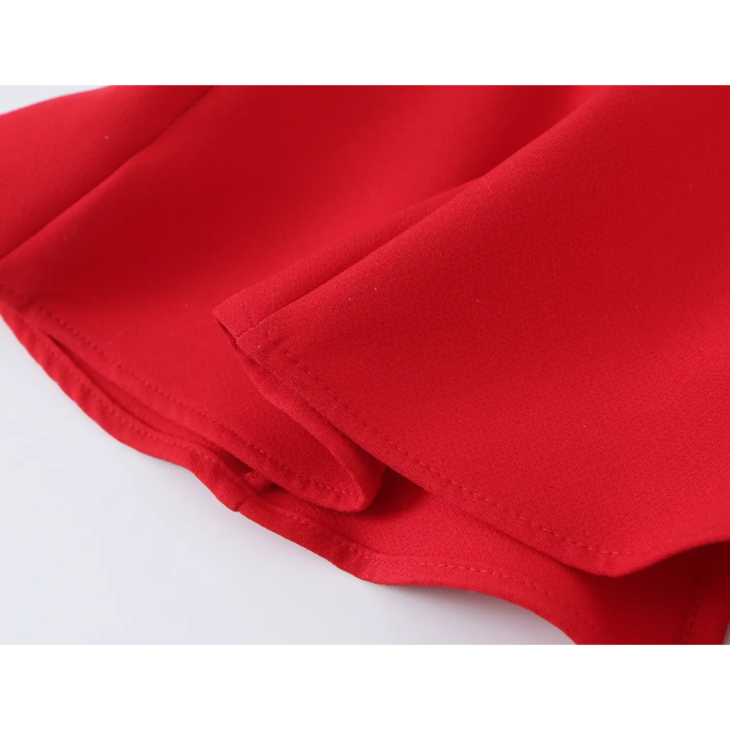 Close‑up fabric texture and double‑stitched hem edge of red halter peplum blouse