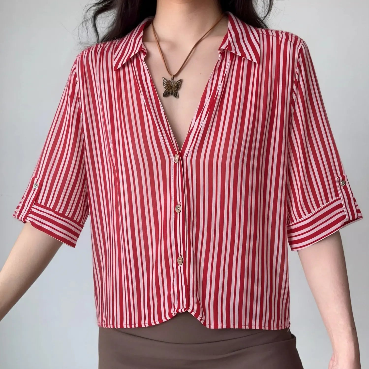 Front lifestyle shot on model of red pink vertical stripe cropped blouse, notched lapel collar, tab short sleeves, casual summer outfit