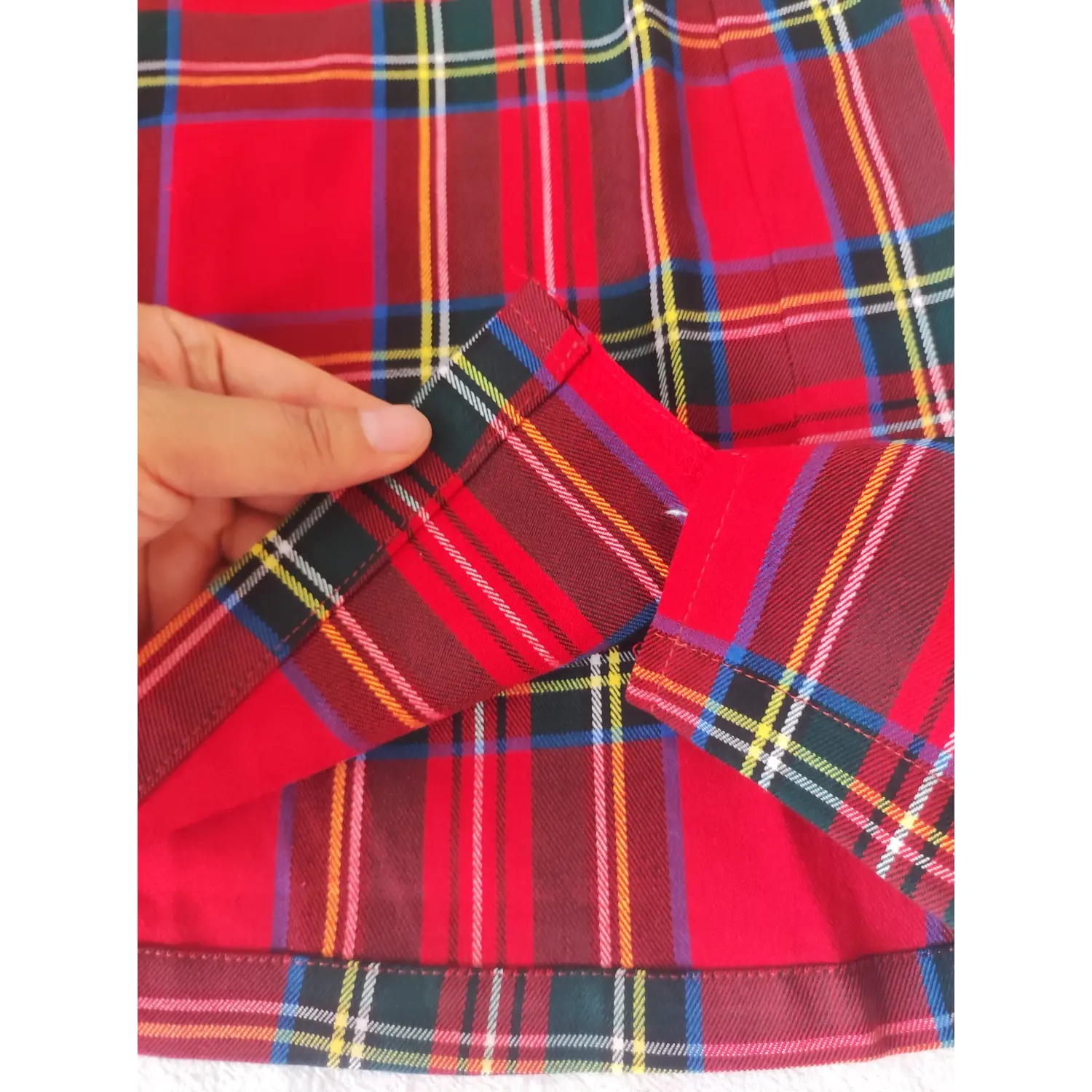 Hand close-up showing hem split design and woven tartan fabric