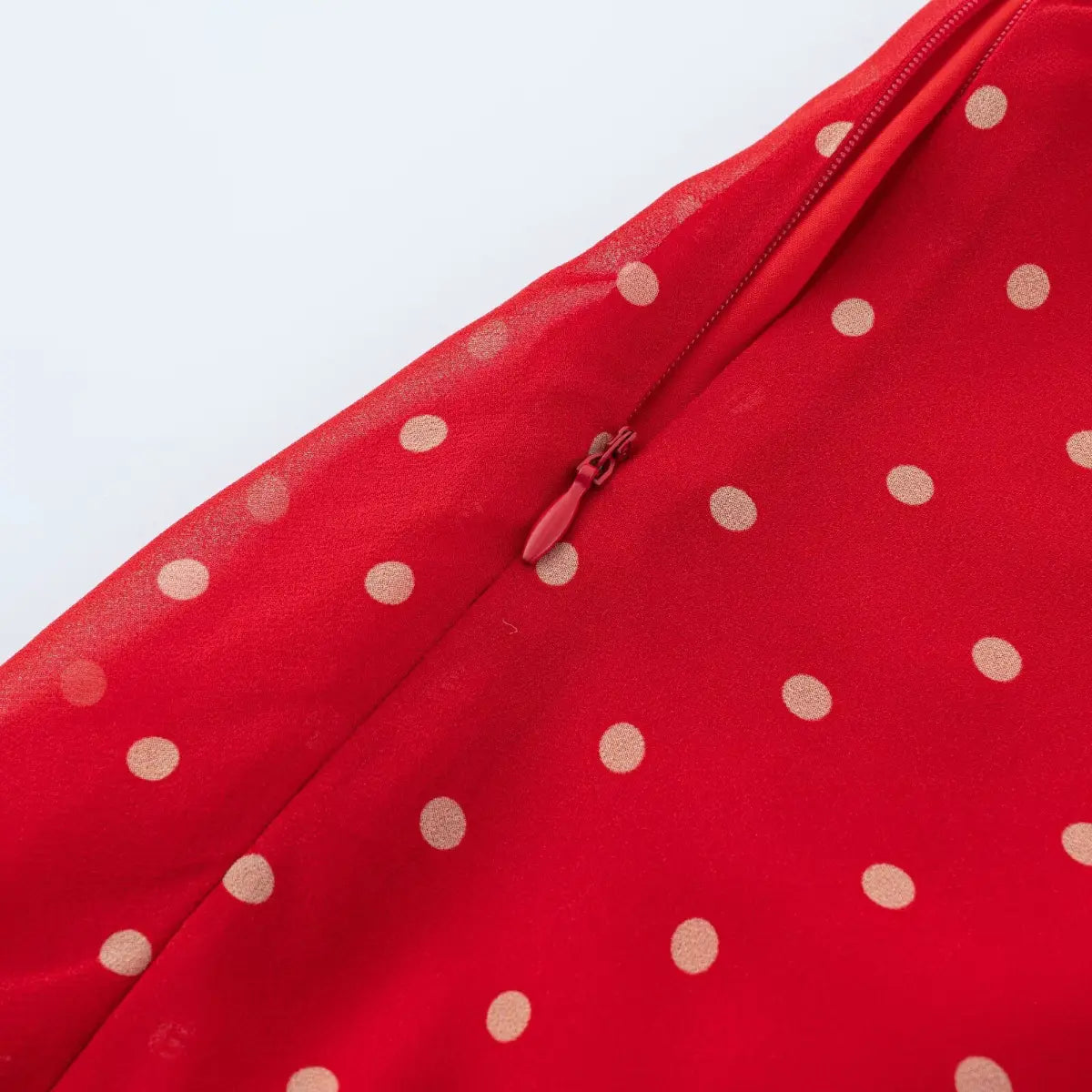 Close-up of lightweight sheer red polka dot chiffon fabric and solid red inner lining texture.
