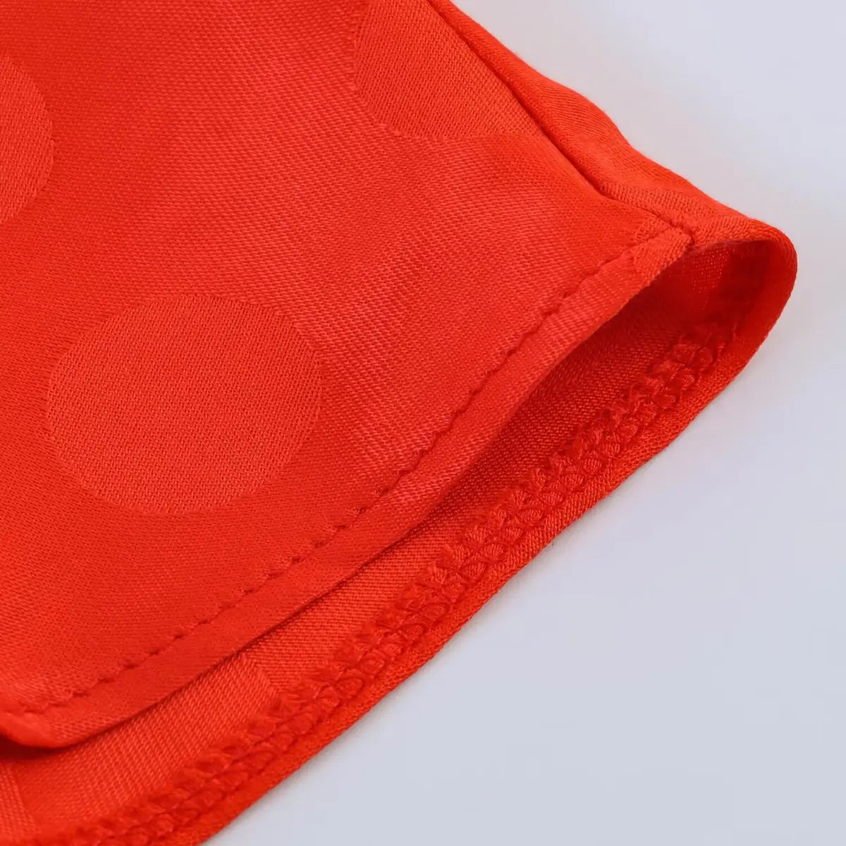 Close-up of the stitched hem and fabric texture on the red polka dot jacquard dress
