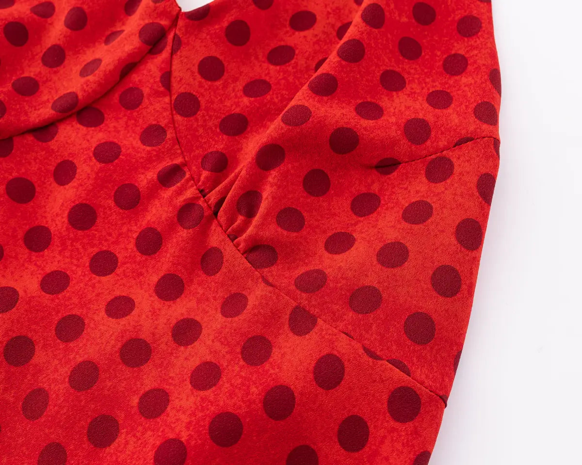 Close-up of the black polka dot print and fabric texture on the red dress