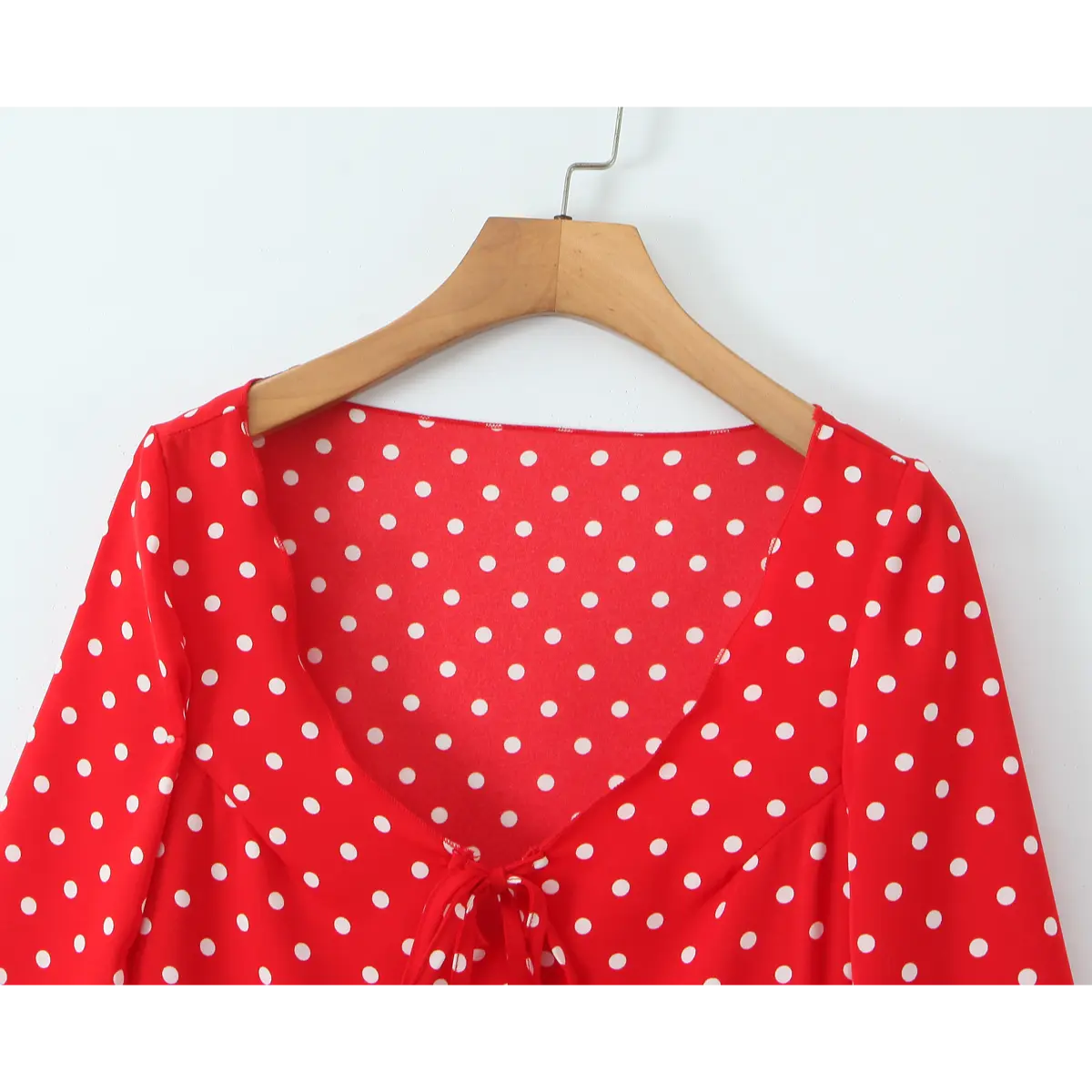 Close-up front view of the U-neckline and tie detail on the red polka dot dress.
