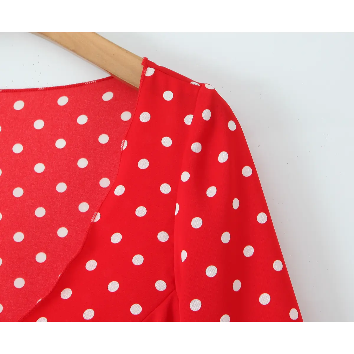 Close-up of the shoulder seam and neckline construction on the red polka dot dress.