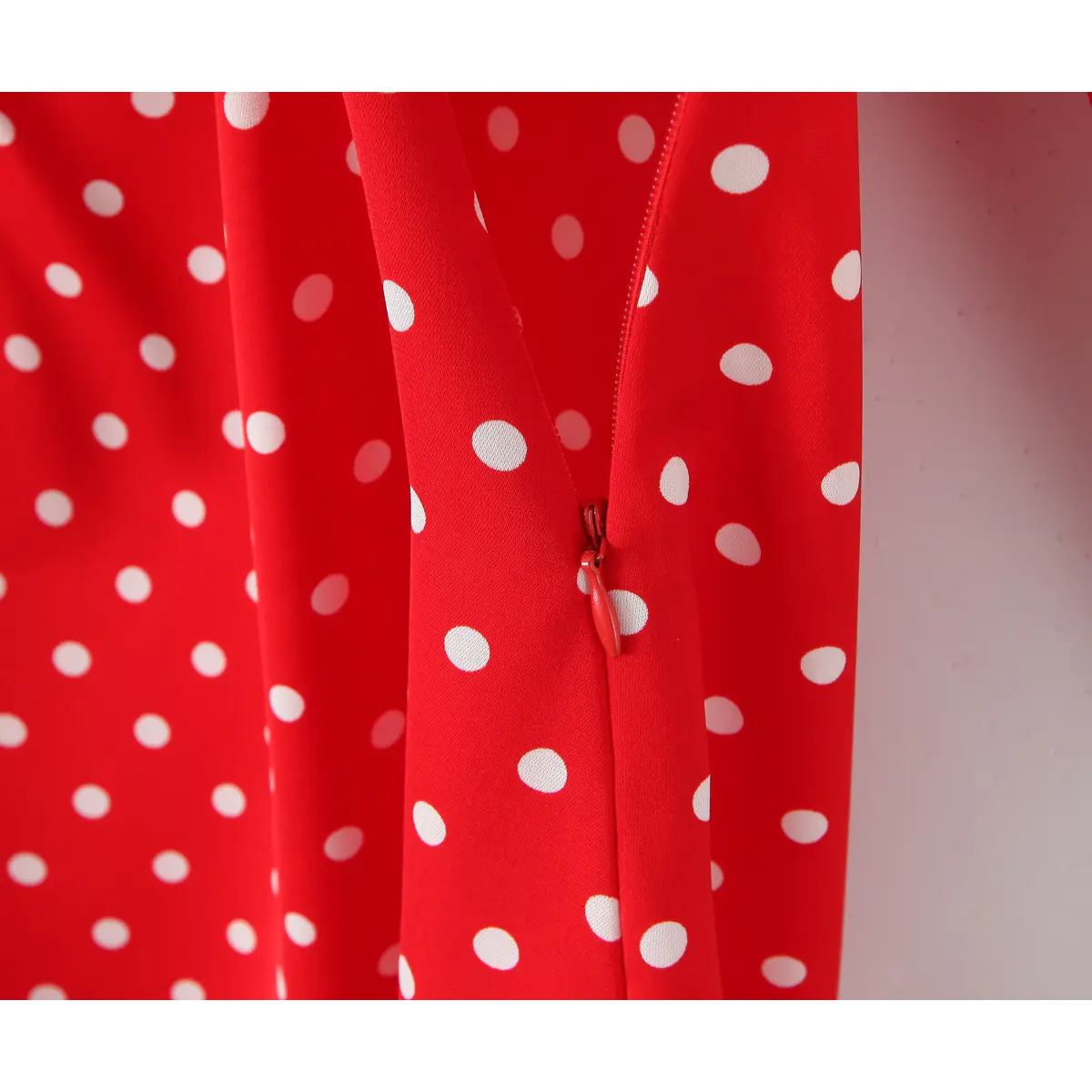 Close-up of the side zipper and polka dot print on the red dress.