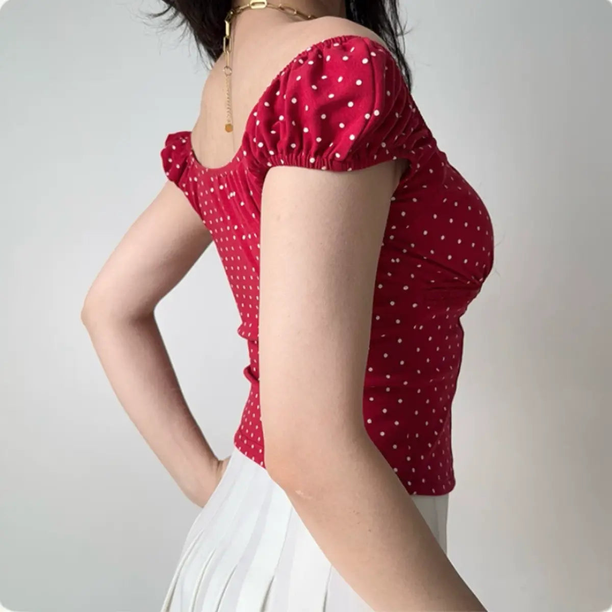 Side view of a woman in a red polka dot puff sleeve top, showing the fitted silhouette and gathered sleeve detail.