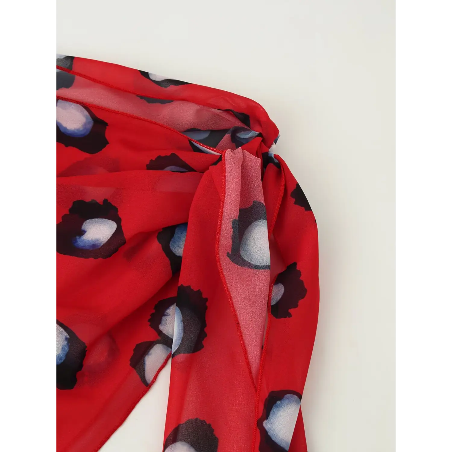 Close up knotted red polka dot chiffon wrap sash for spotted shirt, sheer flowy fabric with print detail