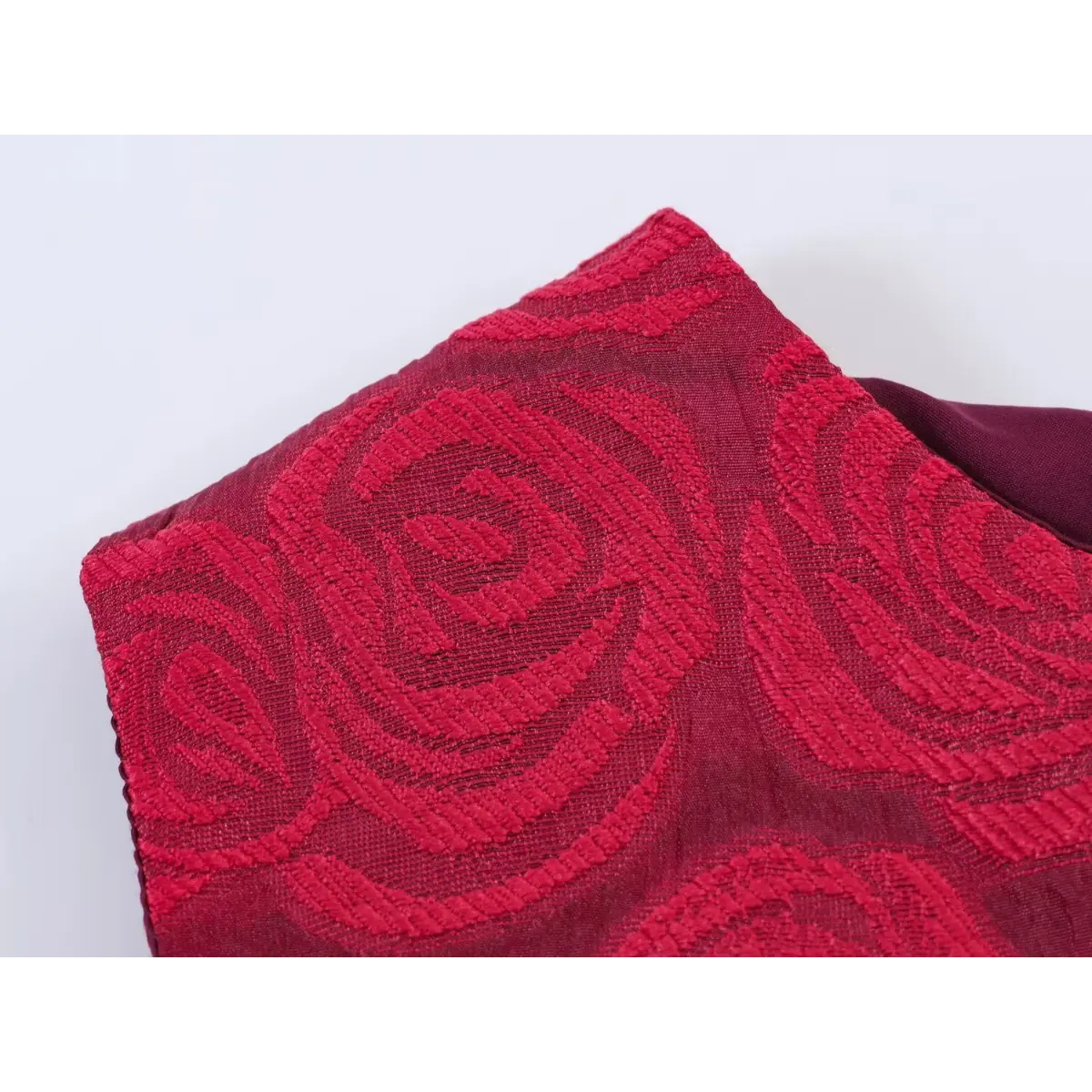 Close-up of the embossed rose brocade fabric and inner lining on a red sleeveless dress.