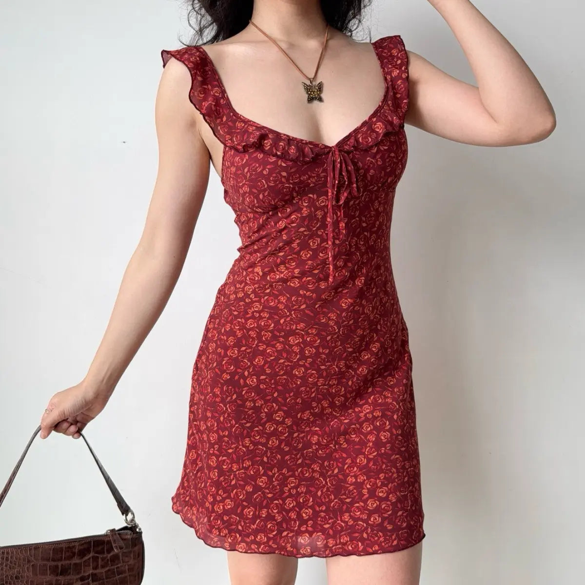 The red floral mini dress paired with a butterfly necklace, highlighting the neckline.