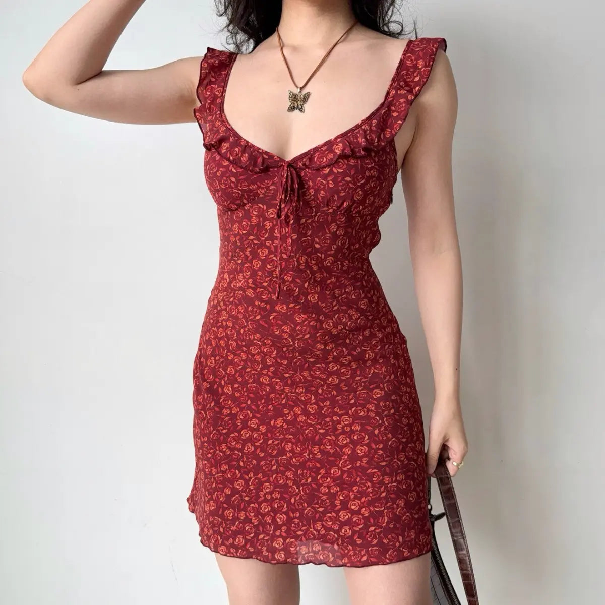 Front view of the red rose print mini dress with ruffled straps and tie detail.