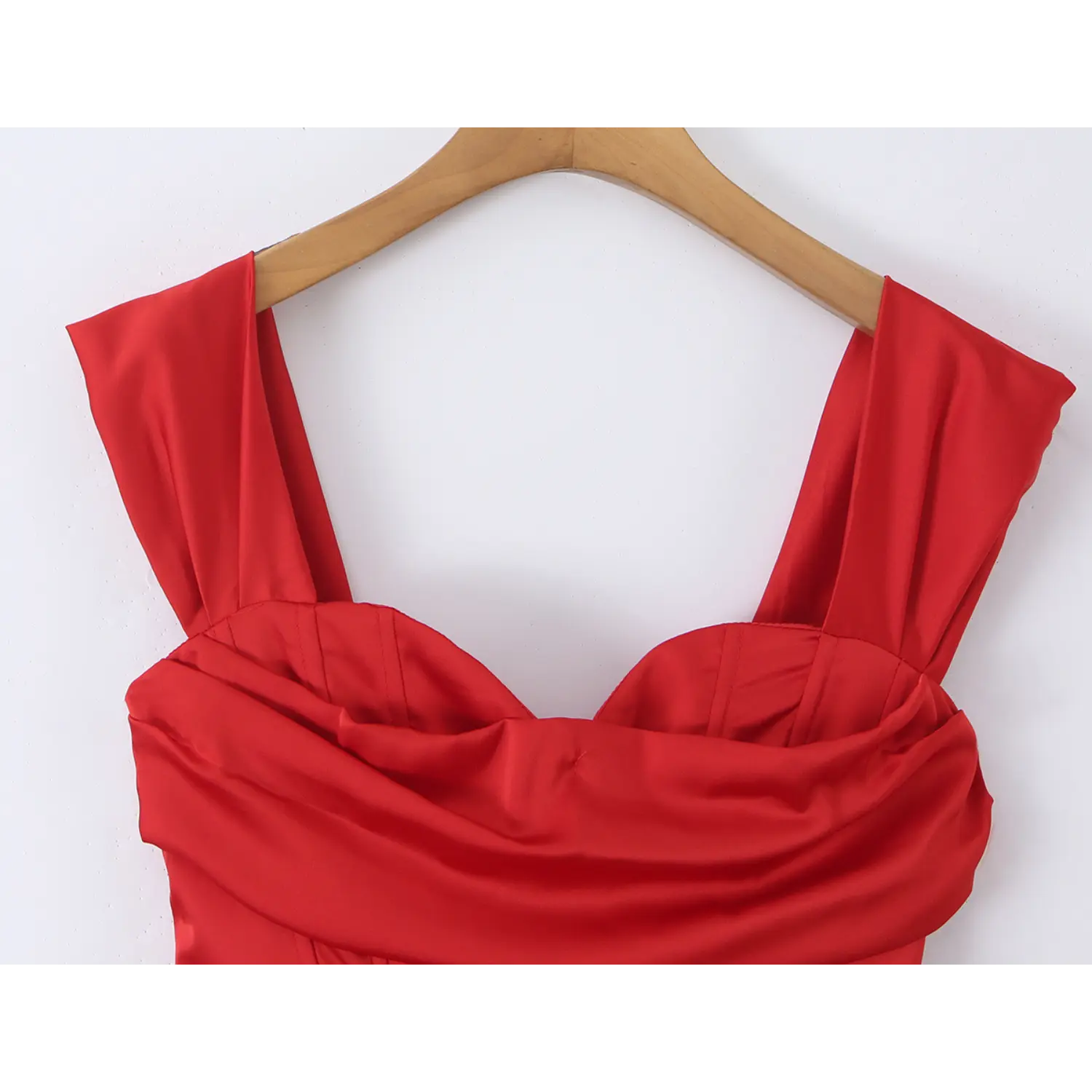 Close-up detail of wide folded shoulder straps and soft draped folded satin bust on red corset mini dress