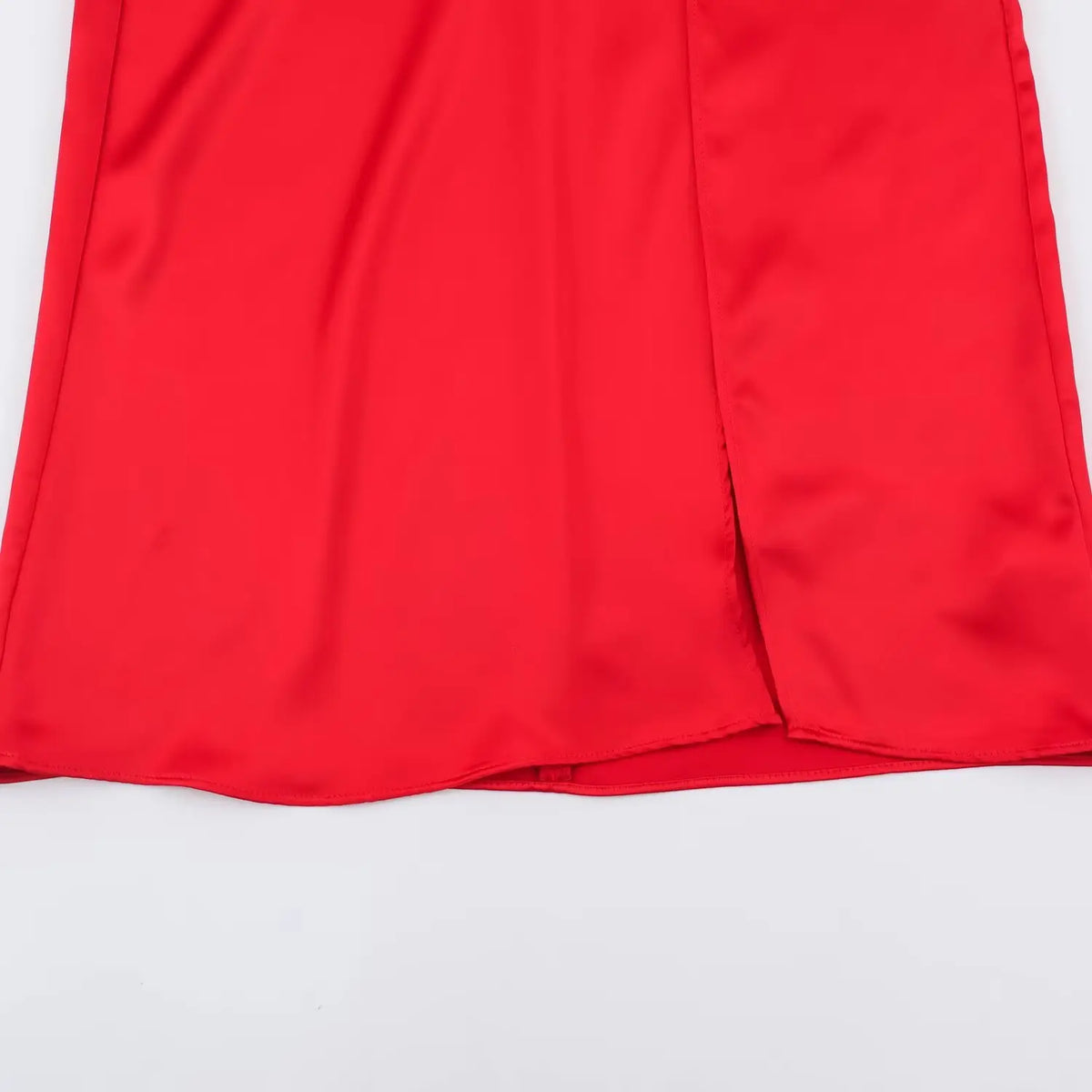 Close-up of front side slit at hem of red satin maxi dress