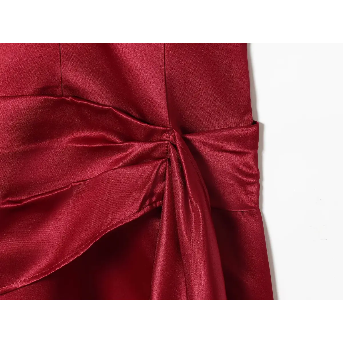 Close-up detail shot of the side tie on a red satin mini dress, showing the knot, gathered fabric, and stitching.