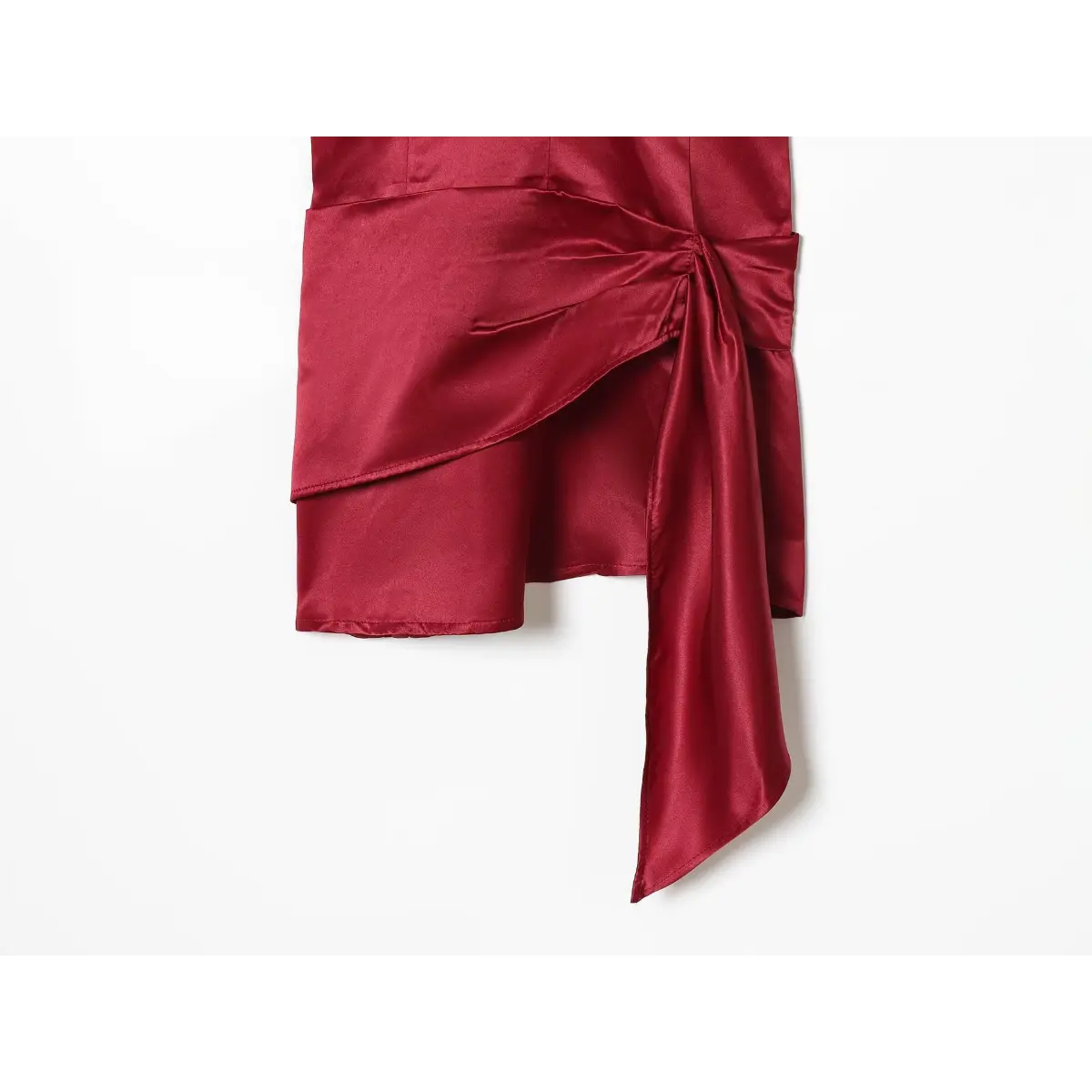 Close-up detail shot of the side tie and draped fabric on a red satin mini dress, showing the knot and asymmetrical hem.