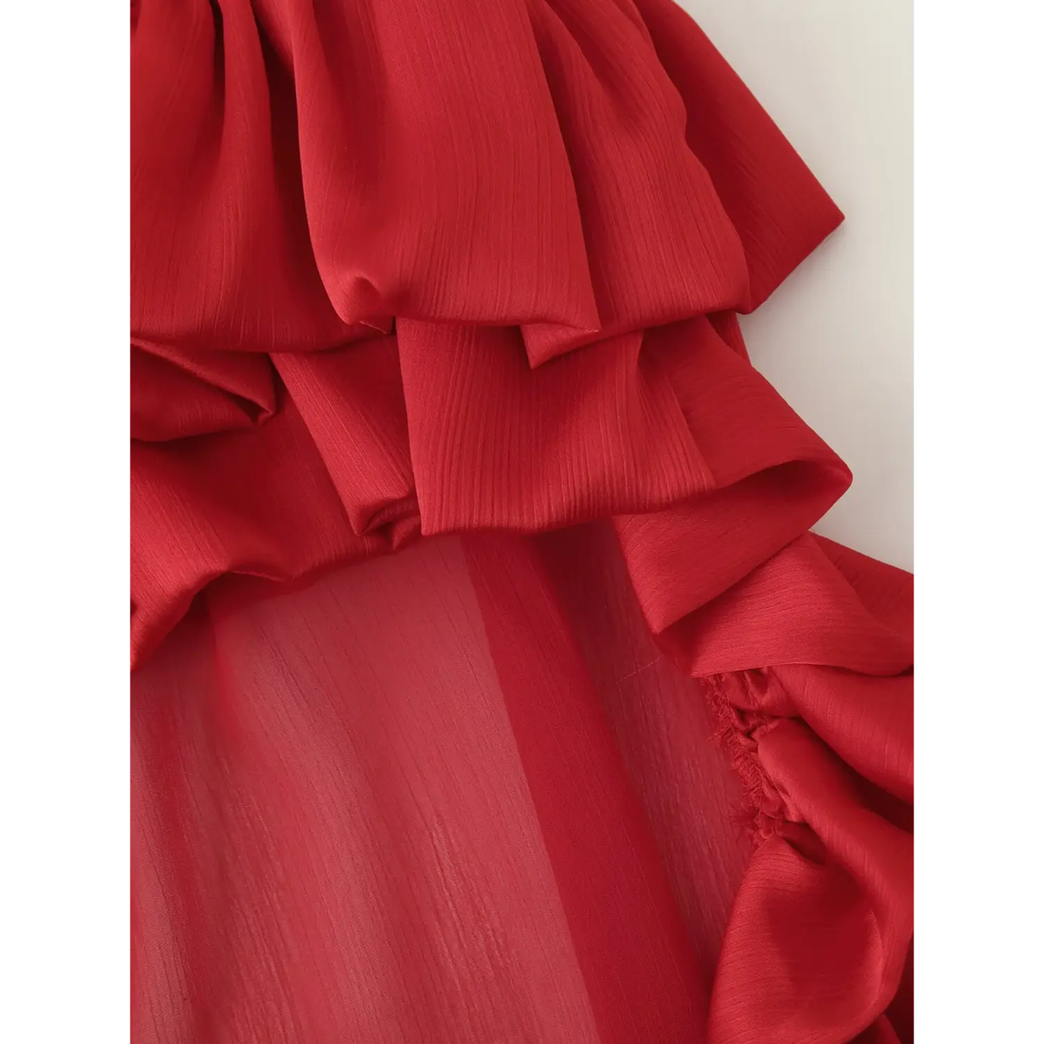 Macro close up of side wavy ruffle and sheer chiffon fabric of red maxi skirt
