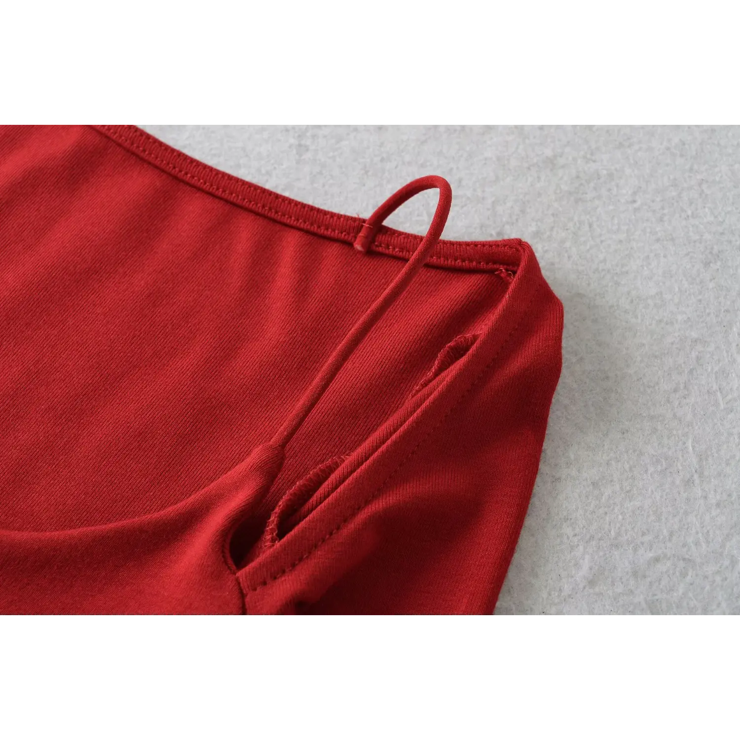 Red cold shoulder top spaghetti strap macro flat shot, thin strap root reinforced stitching double layer binding stretch knit texture white background detail