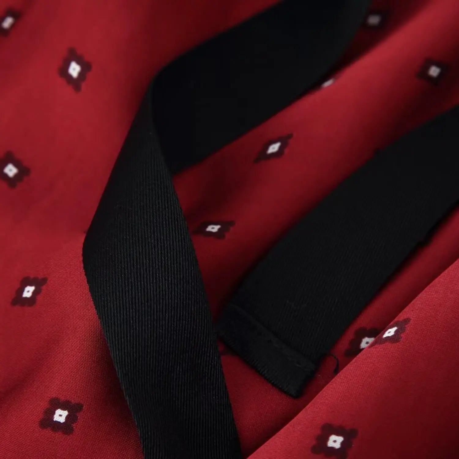 Drape close-up of red ground geometric square print and matte black waist tie ribbon