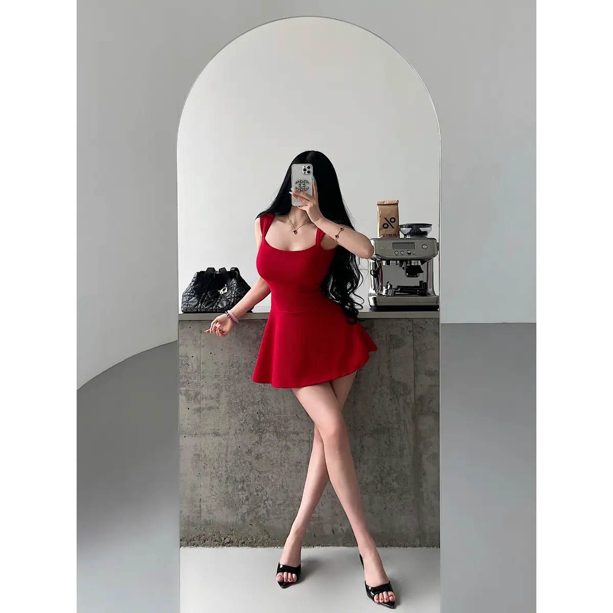 Full-body shot of a woman wearing a bright red square-neck, low-back fit-and-flare mini dress taking a mirror selfie.