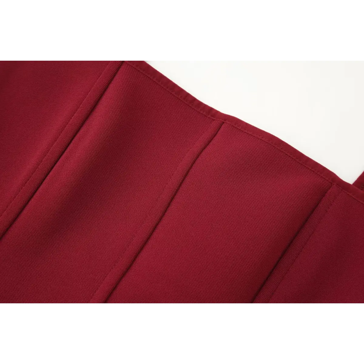 Close-up of the front vertical boning seams on the red bustier cami top, showing the structured stitching and smooth knit fabric