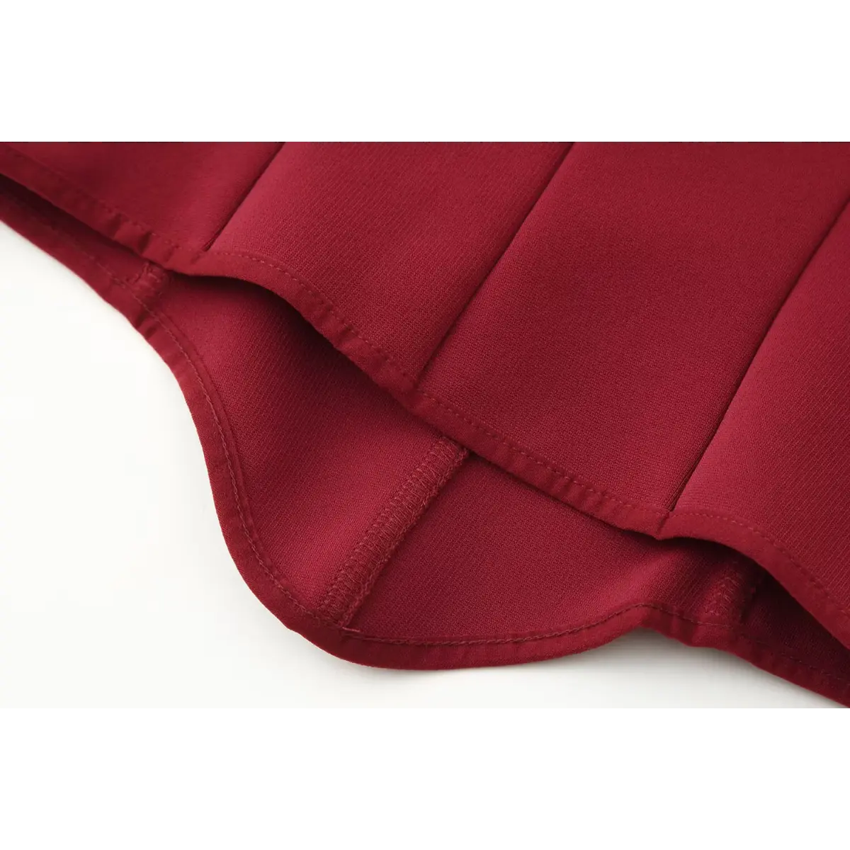 Close-up of the hem on the red bustier cami top, showing the curved bottom edge and clean finished stitching