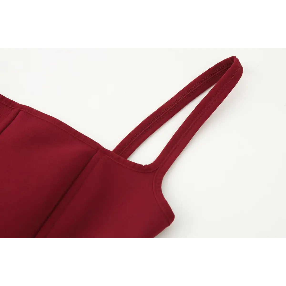 Close-up of the spaghetti strap on the red bustier cami top, showing the reinforced stitching and smooth fabric