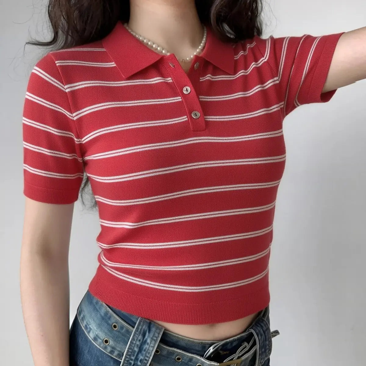 The red and white striped knit polo shirt worn by a model, styled with jeans and layered pearl necklaces