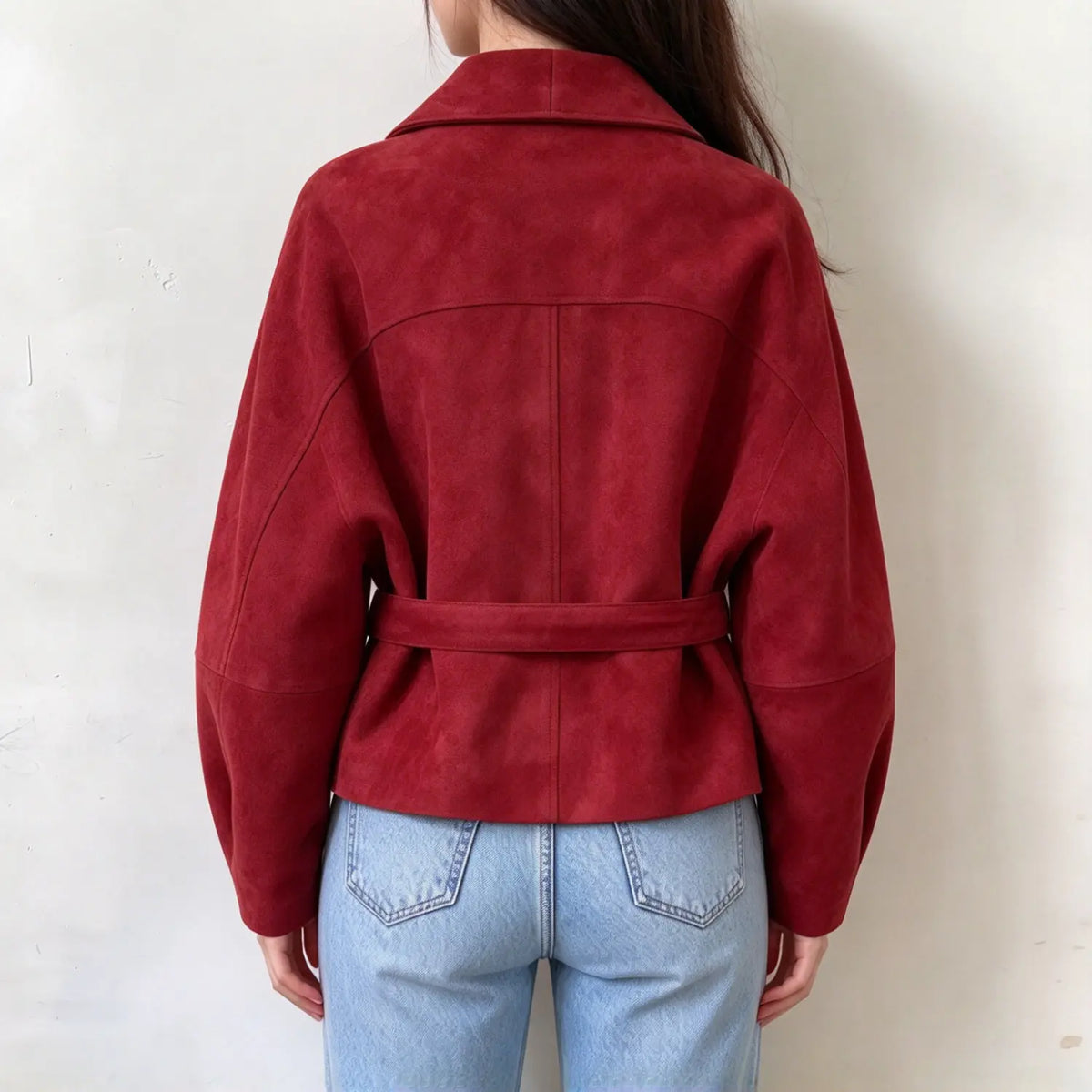 Female model back view, red faux suede cropped jacket, tailored back seams and matching waist belt, long loose sleeves