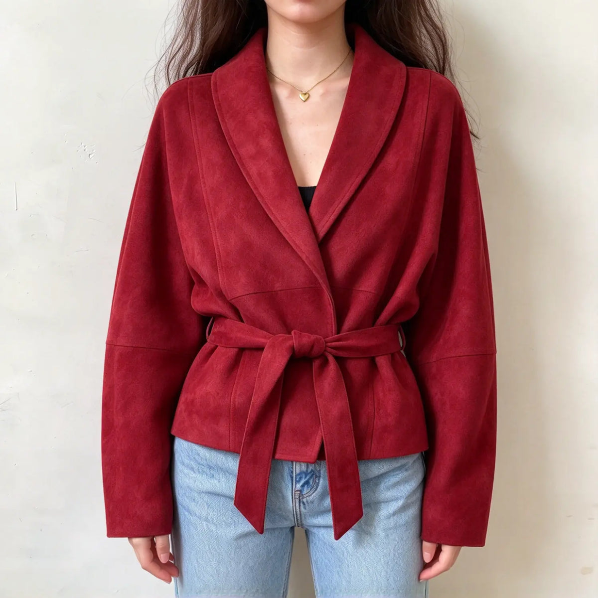 Female model wears red faux suede wrap jacket, shawl lapel collar, self tie waist belt, relaxed long sleeves, front torso shot
