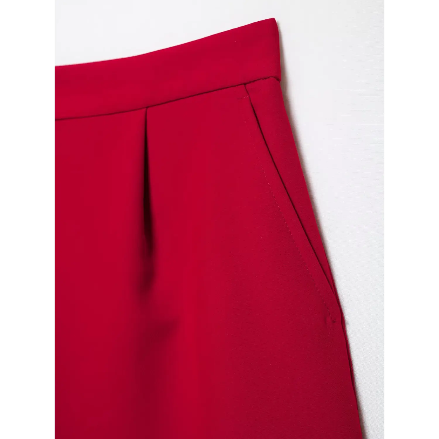 Close‑up side pocket detail of red suit shorts, neat pocket stitching, front pleat, structured suiting fabric, white background