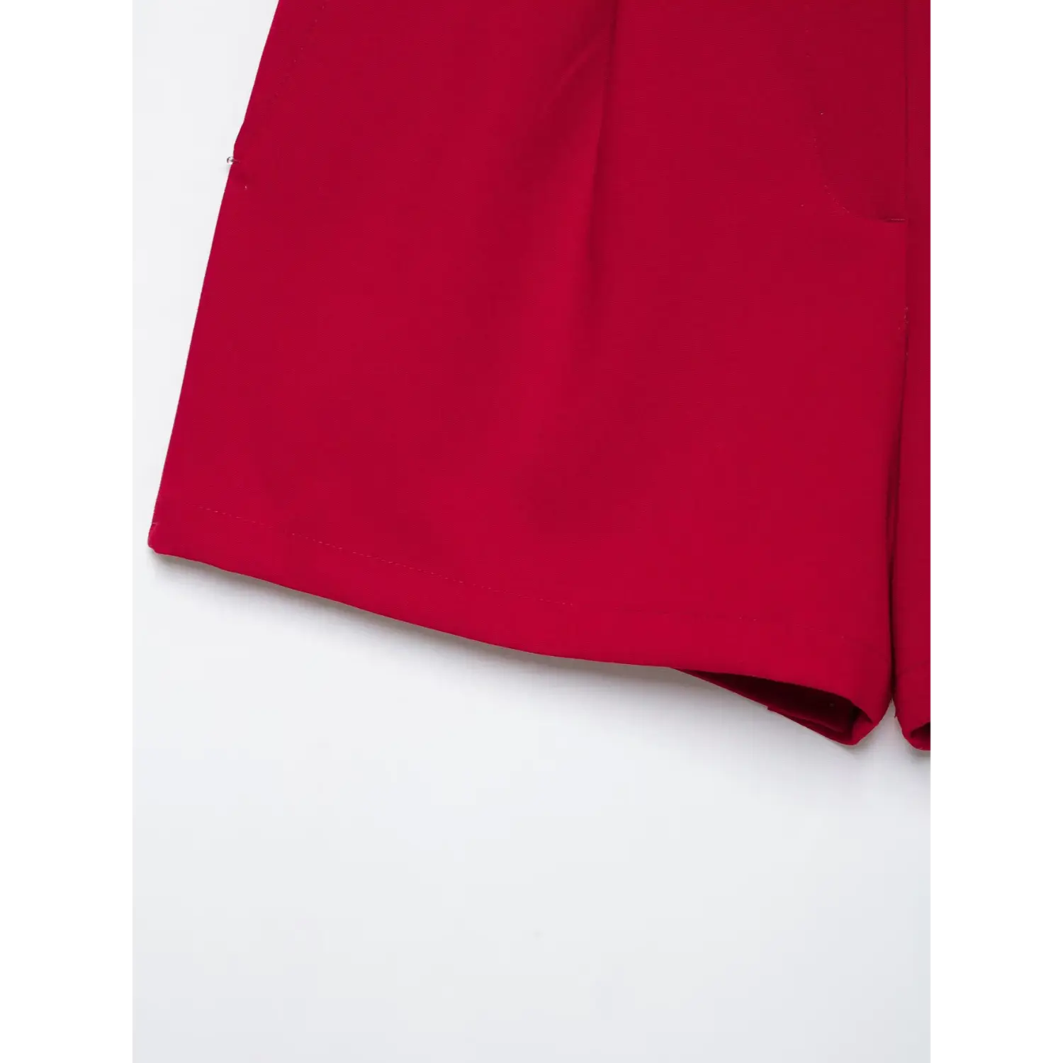 Close‑up bottom hem of red suit shorts, neat finished hem, structured suiting fabric, white background
