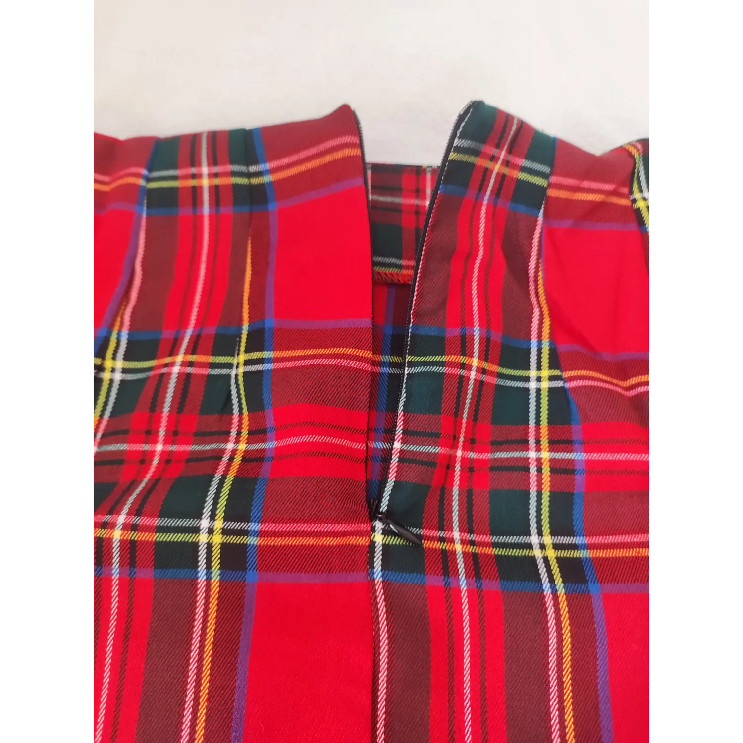 Close-up view of red plaid mini skirt, invisible back zipper and tartan fabric texture