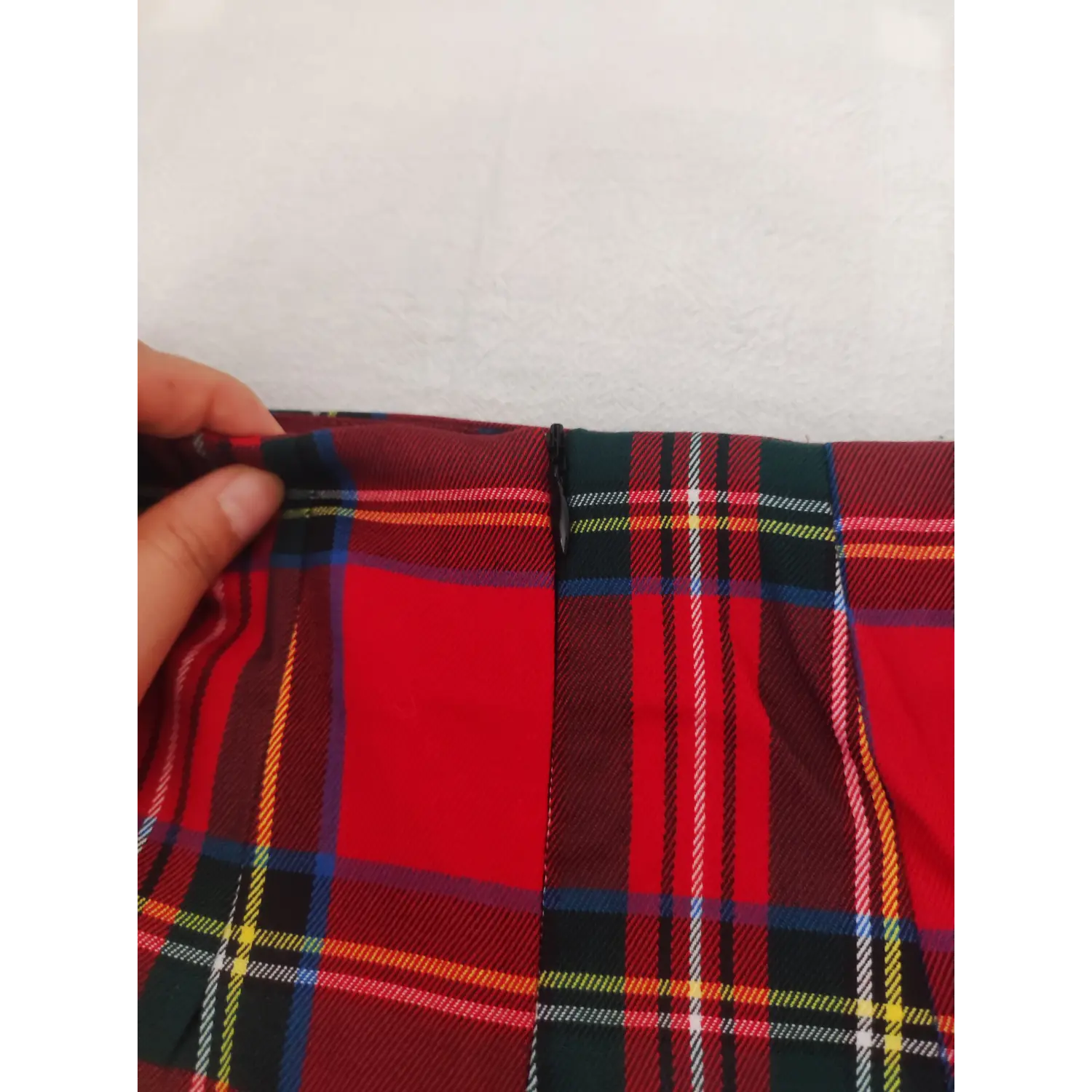 Hand held close-up, invisible rear zipper on red plaid mini skirt