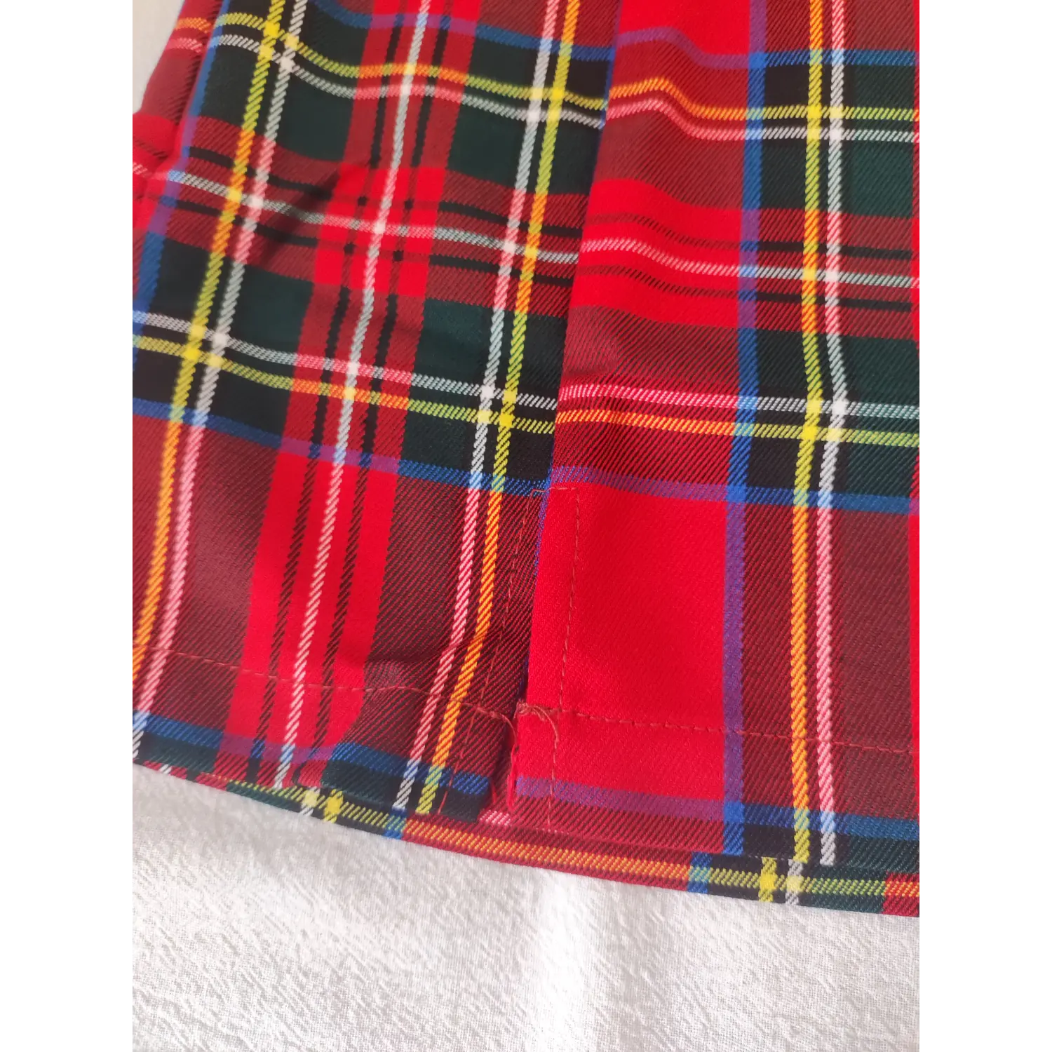 Macro detail of side slit stitching on red plaid mini skirt